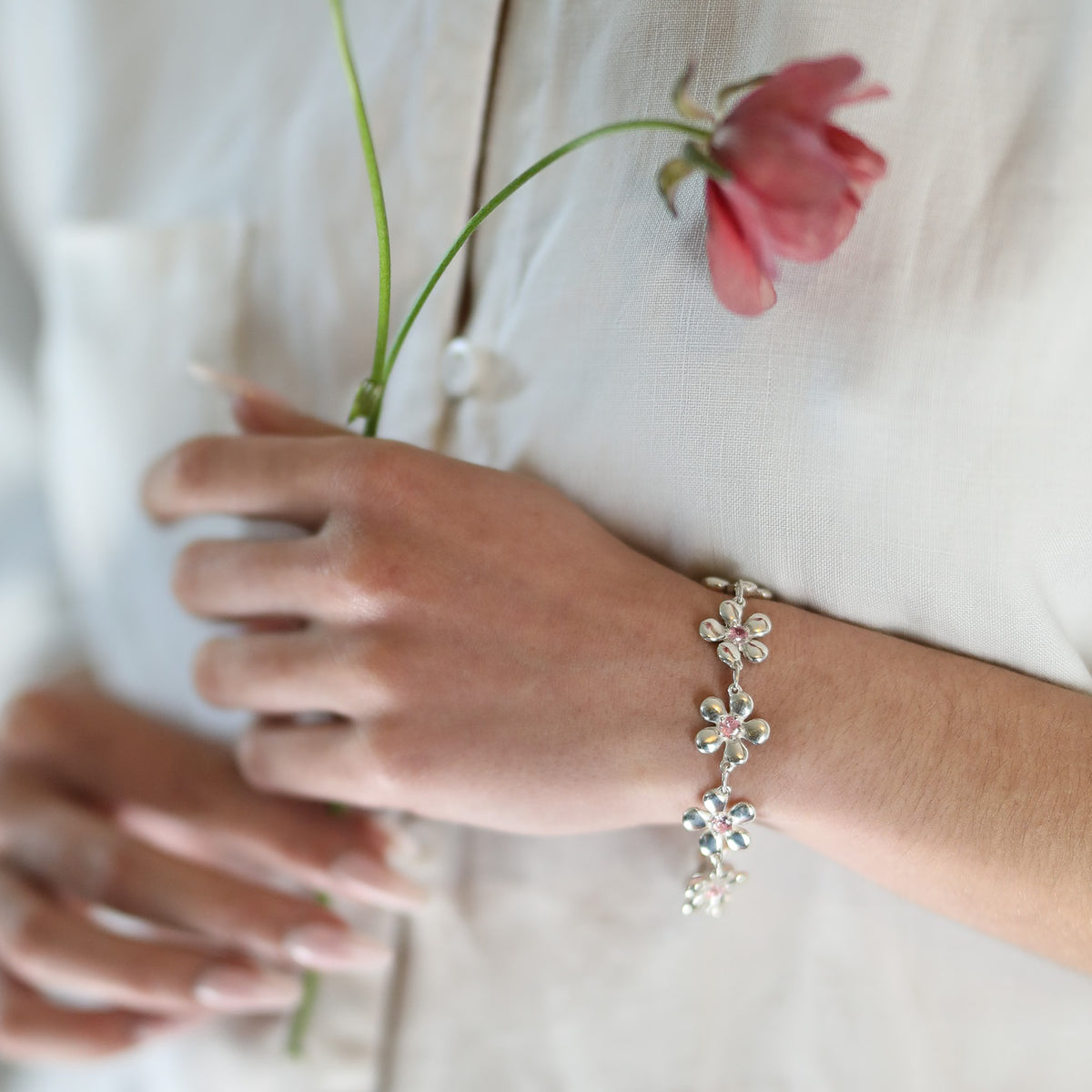 Bracelet Harmonie en argent 925, fleur serti de pierres d'intention, porté sur lin blanc — Collection Éclosion