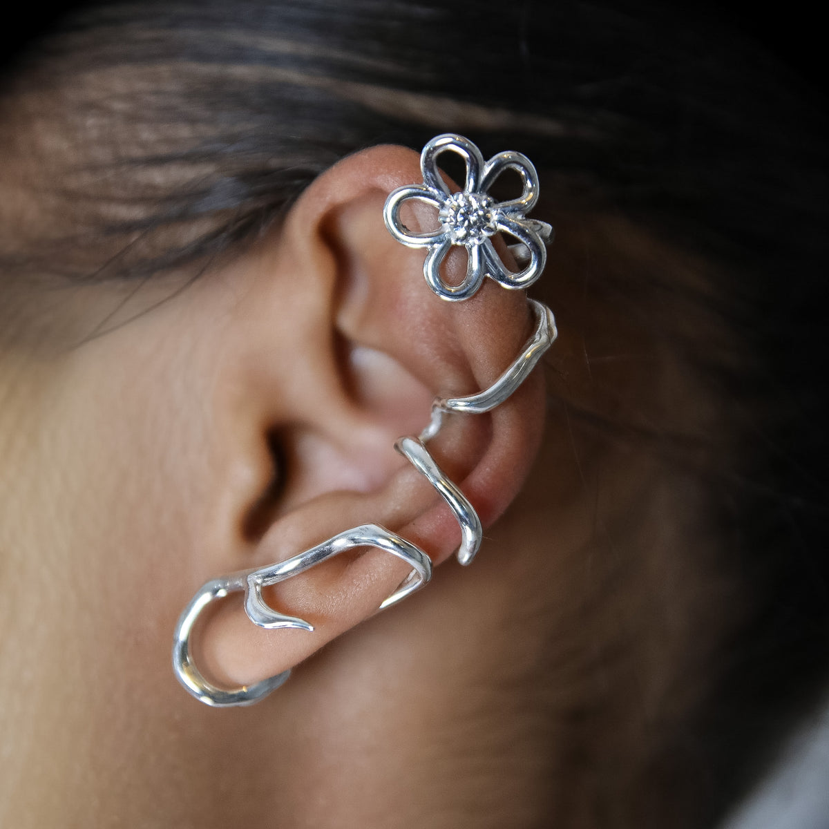 Ear cuff Trajectoire en argent 925, fleur serti de pierres d'intention, porté gros plan — Collection Éclosion