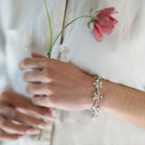Bracelet Harmonie en argent 925, fleur serti de pierres d'intention, porté sur lin blanc — Collection Éclosion